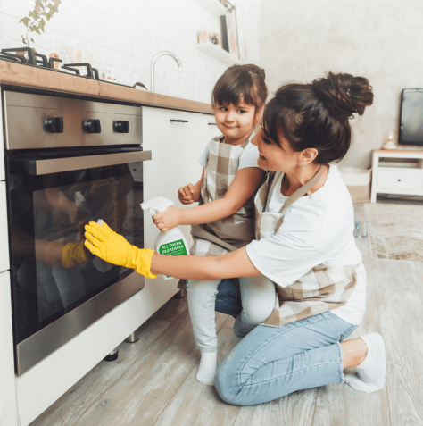 Mom and daughter using All Green Degreaser non-toxic spray to clean an oven